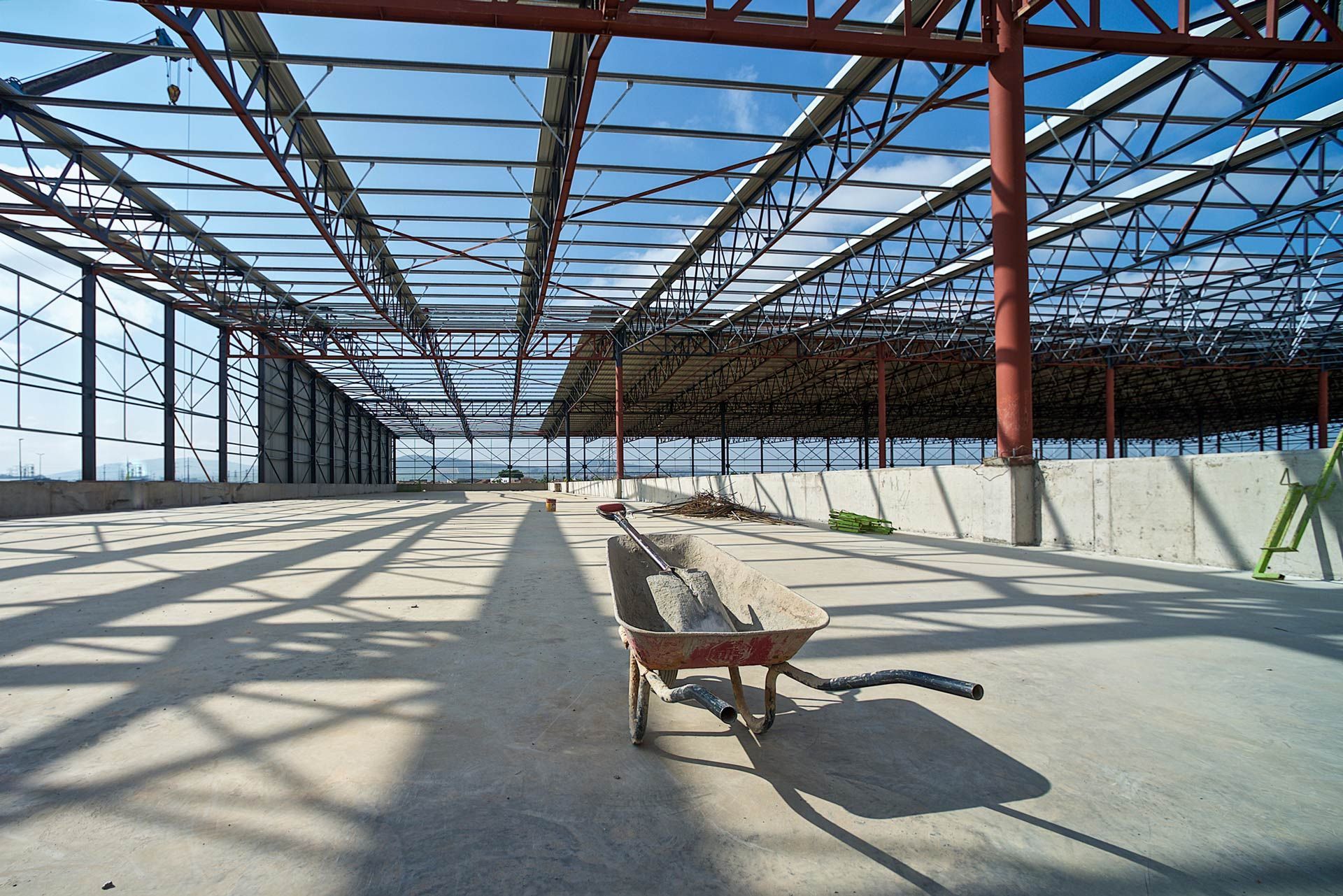 A wheelbarrow is sitting in the middle of an empty building under construction.