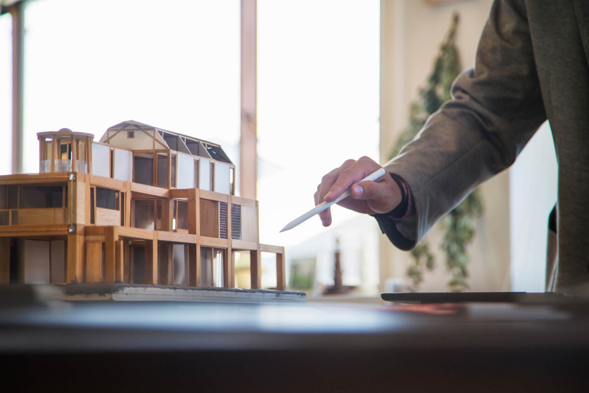 A person is holding a pen over a model of a house.