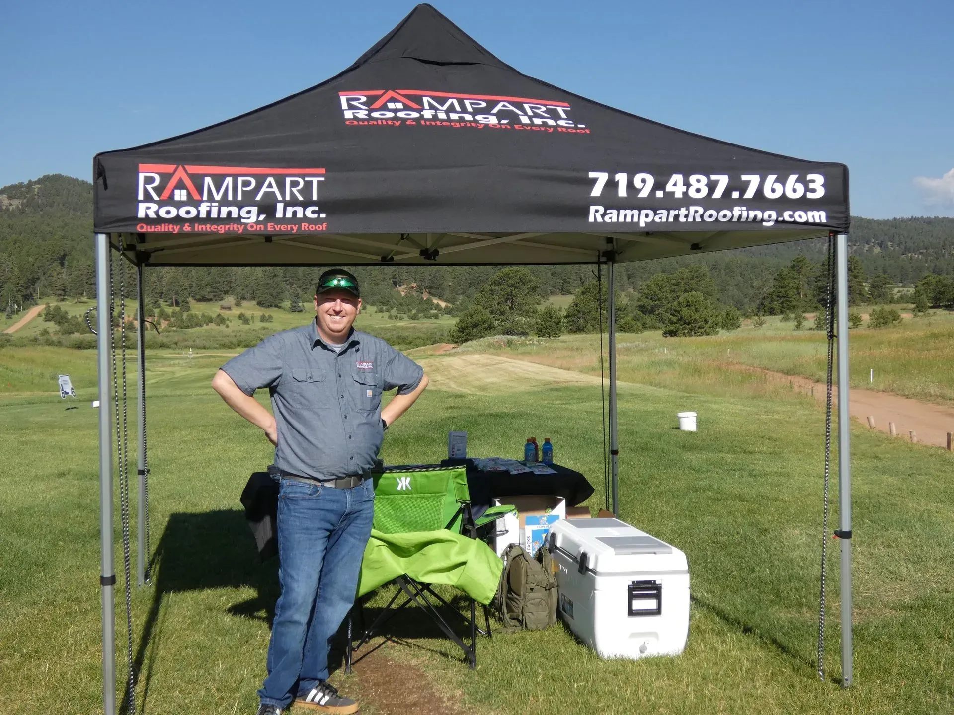Man in front of Rampart Roofing tent at an outdoor event.