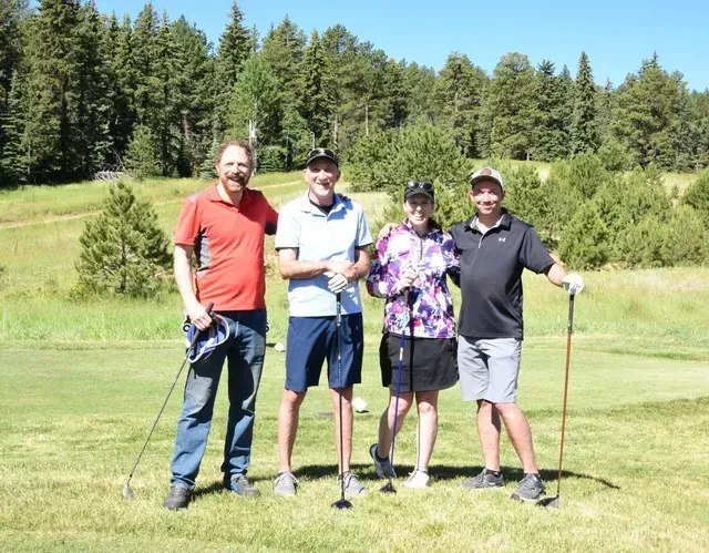 Four golfers on a green golf course on a sunny day.