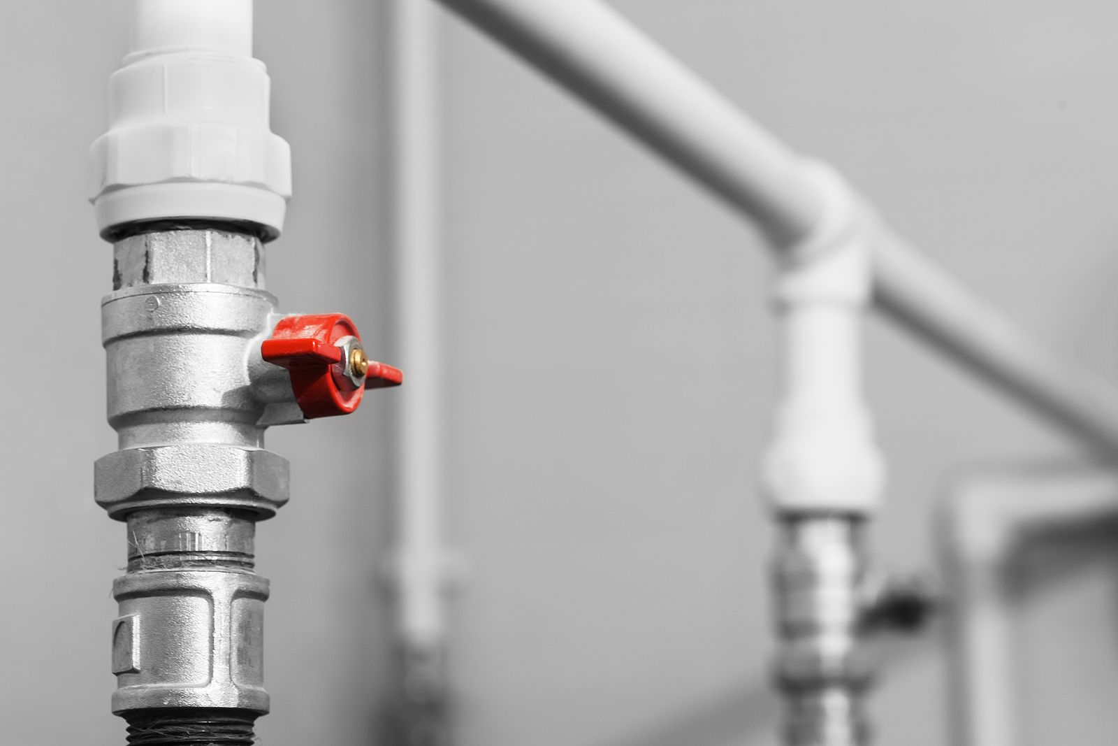 A close up of a red valve on a pipe.