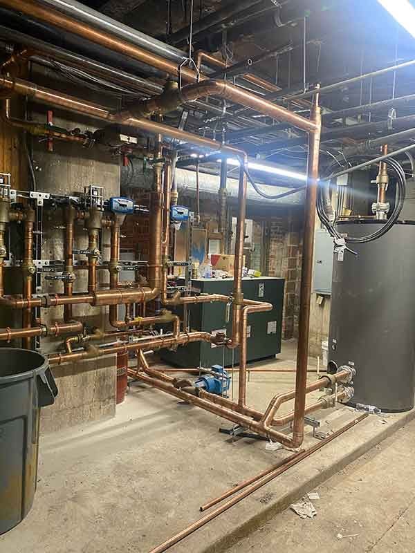 A room filled with lots of pipes and a trash can.