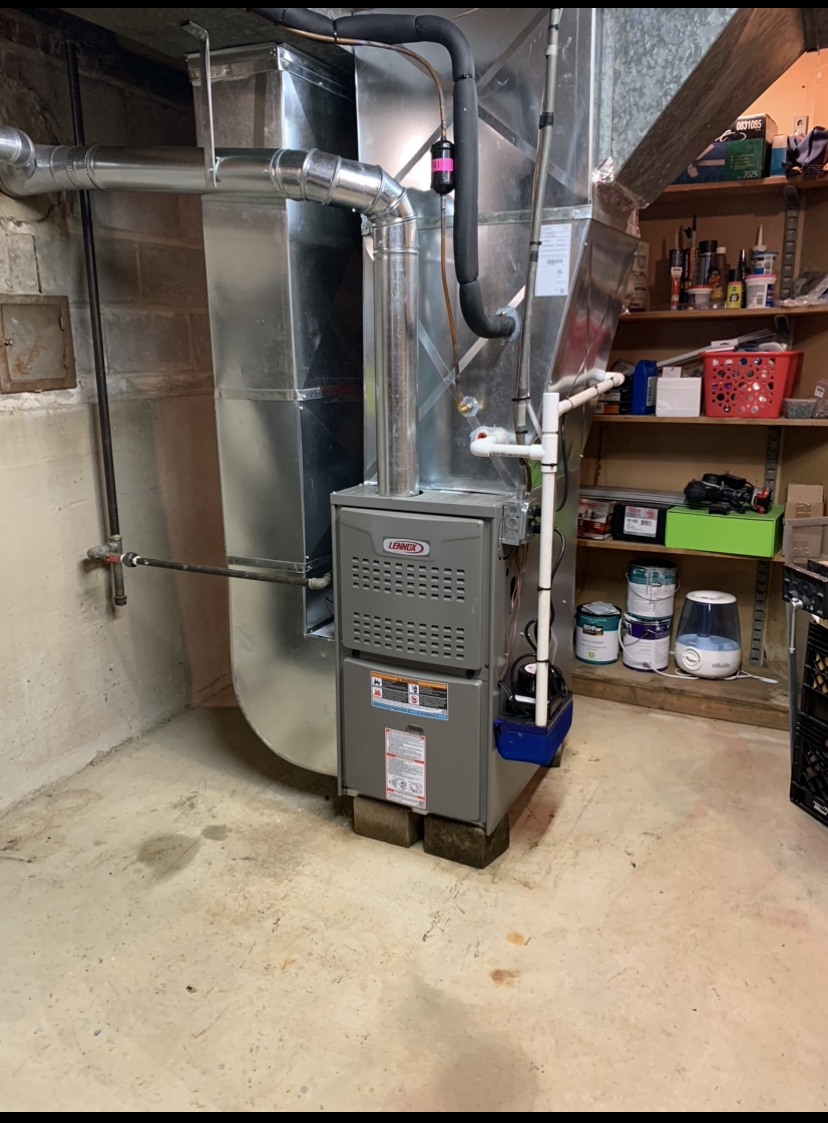 A furnace is sitting in the corner of a room in a basement.
