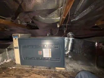 An air conditioner is sitting in the attic of a house.