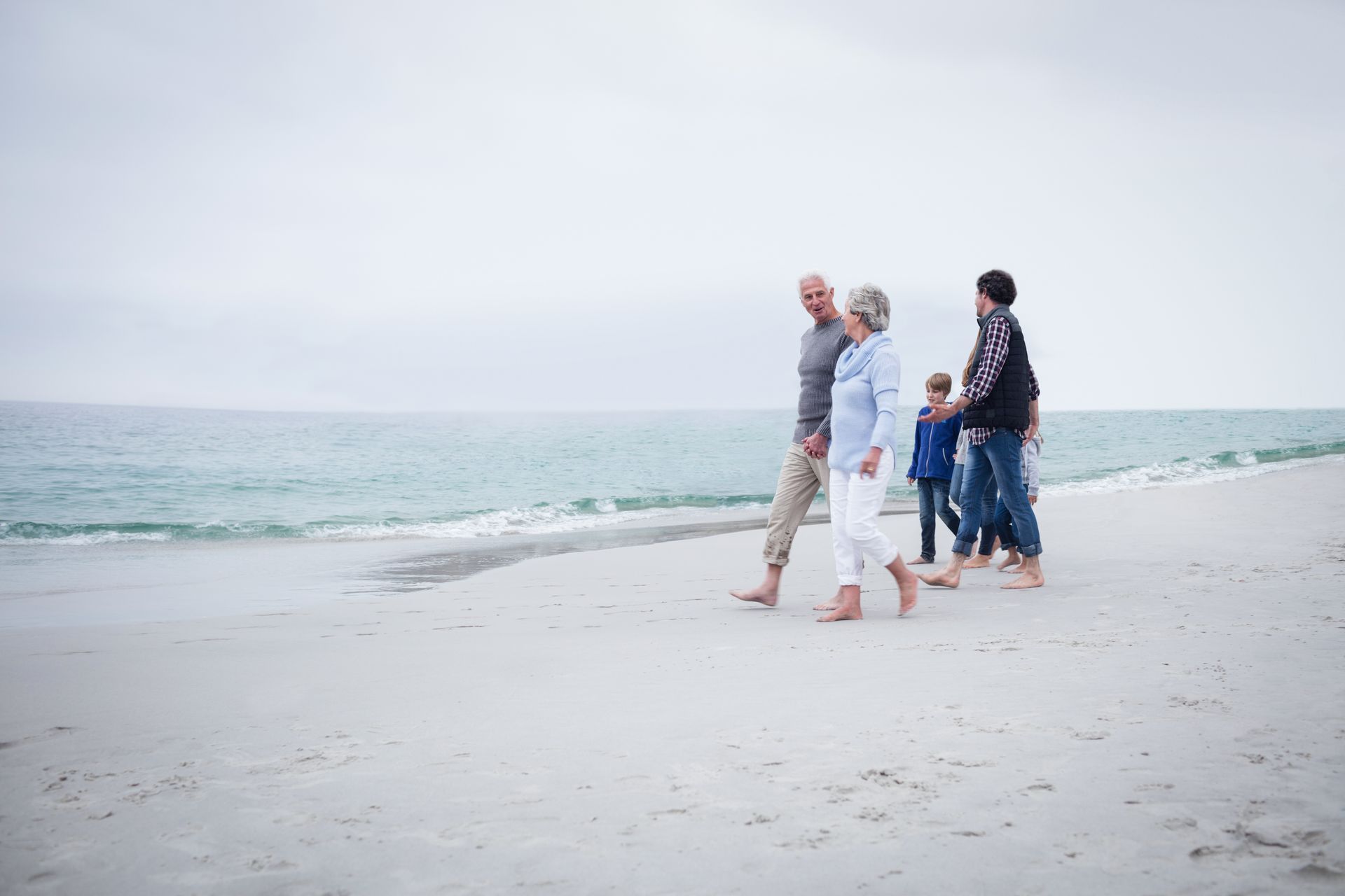 A family is walking on the beach barefoot.