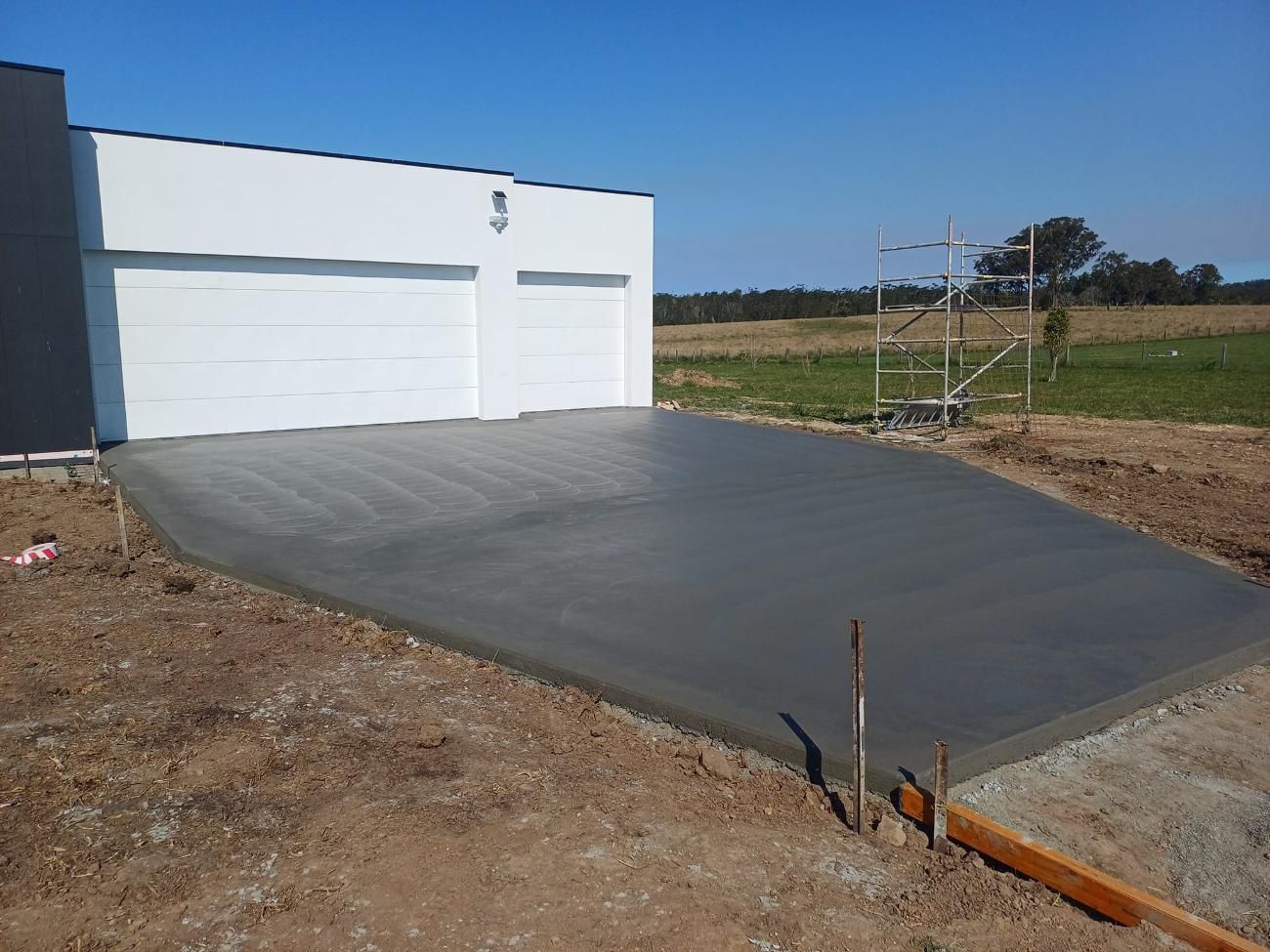 Freshly Poured Concrete Driveway in Front of a White Garage on a Sunny Day — Kempsey Concrete Contractors In Macksville, NSW
