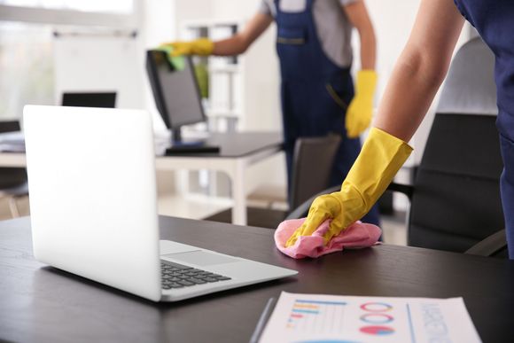 A person is cleaning a desk with a cloth in an office.