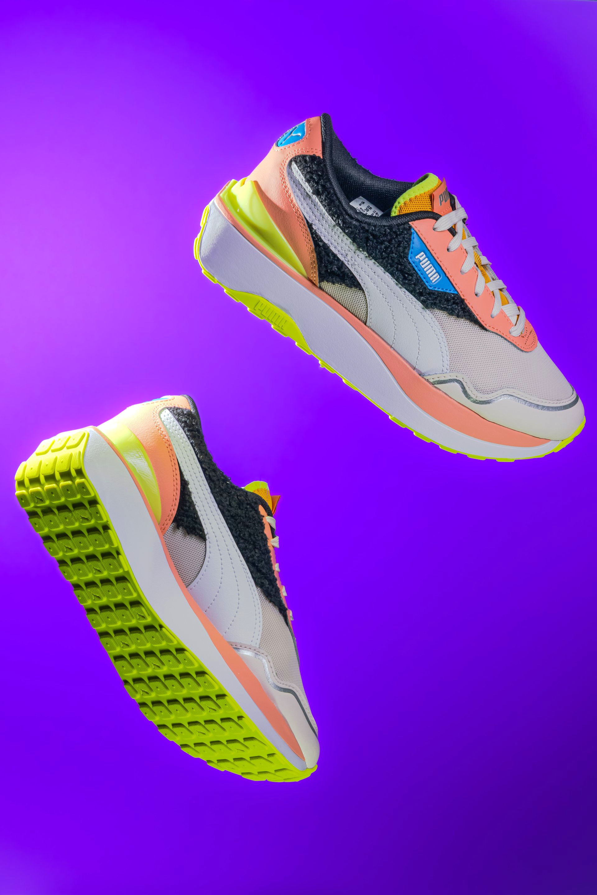 A pair of sneakers are floating in the air on a purple background.