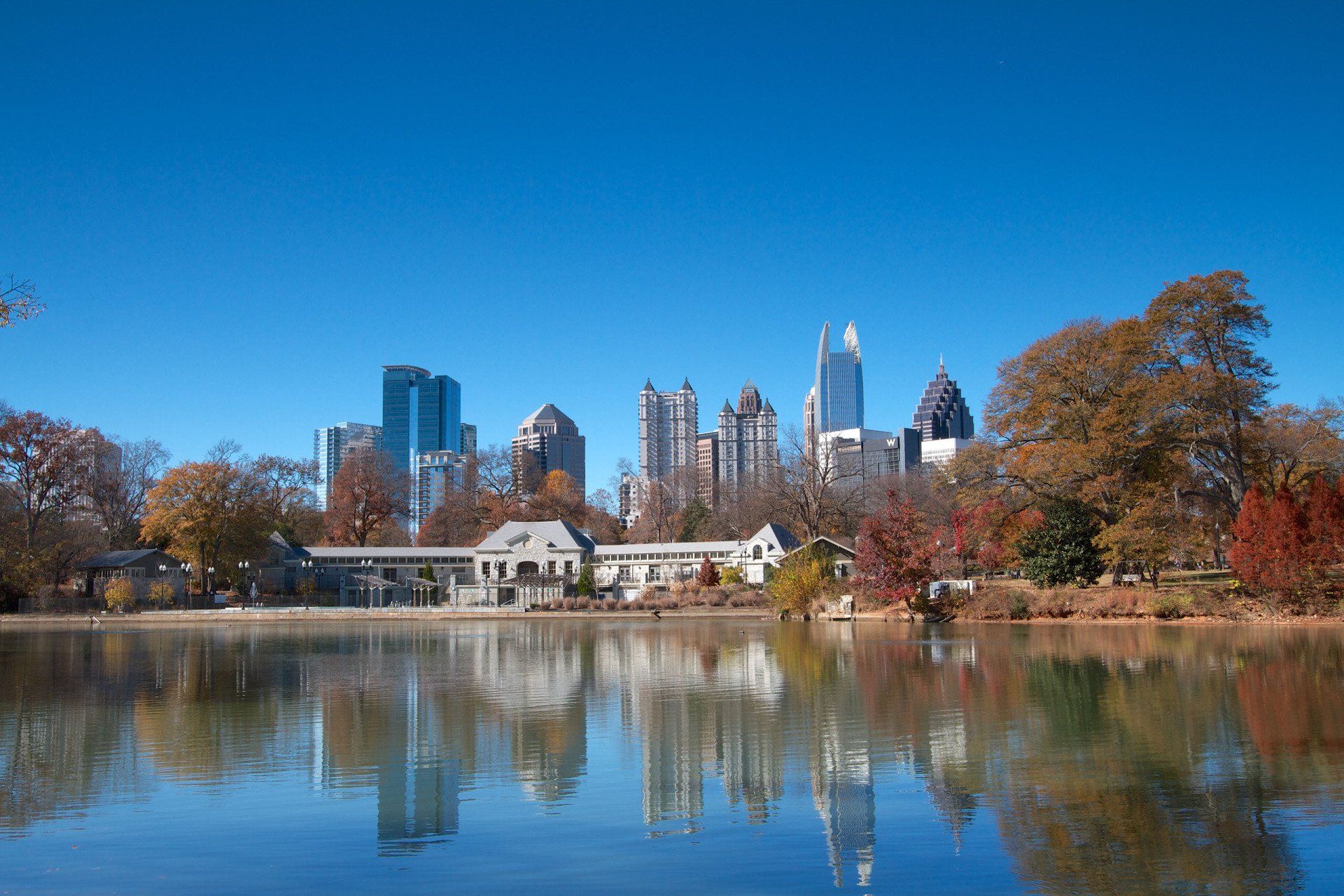 a city skyline is reflected in a lake surrounded by trees
