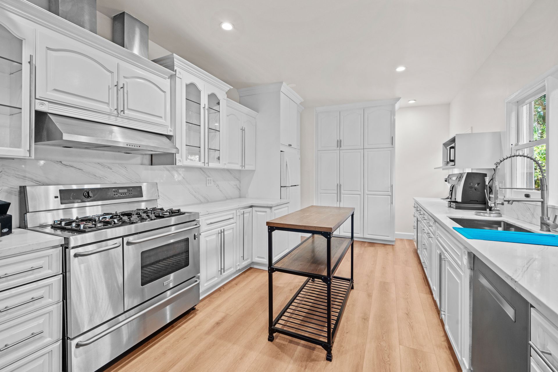 A kitchen with white cabinets , stainless steel appliances , and a wooden island.