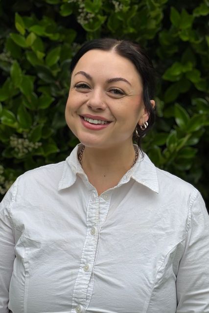 The woman is wearing a white shirt and smiling for the camera.