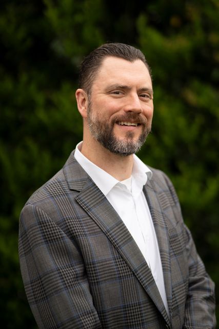 A man in a suit and white shirt is smiling for the camera.