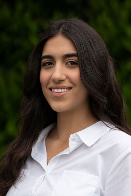 The woman is wearing a white shirt and smiling for the camera.