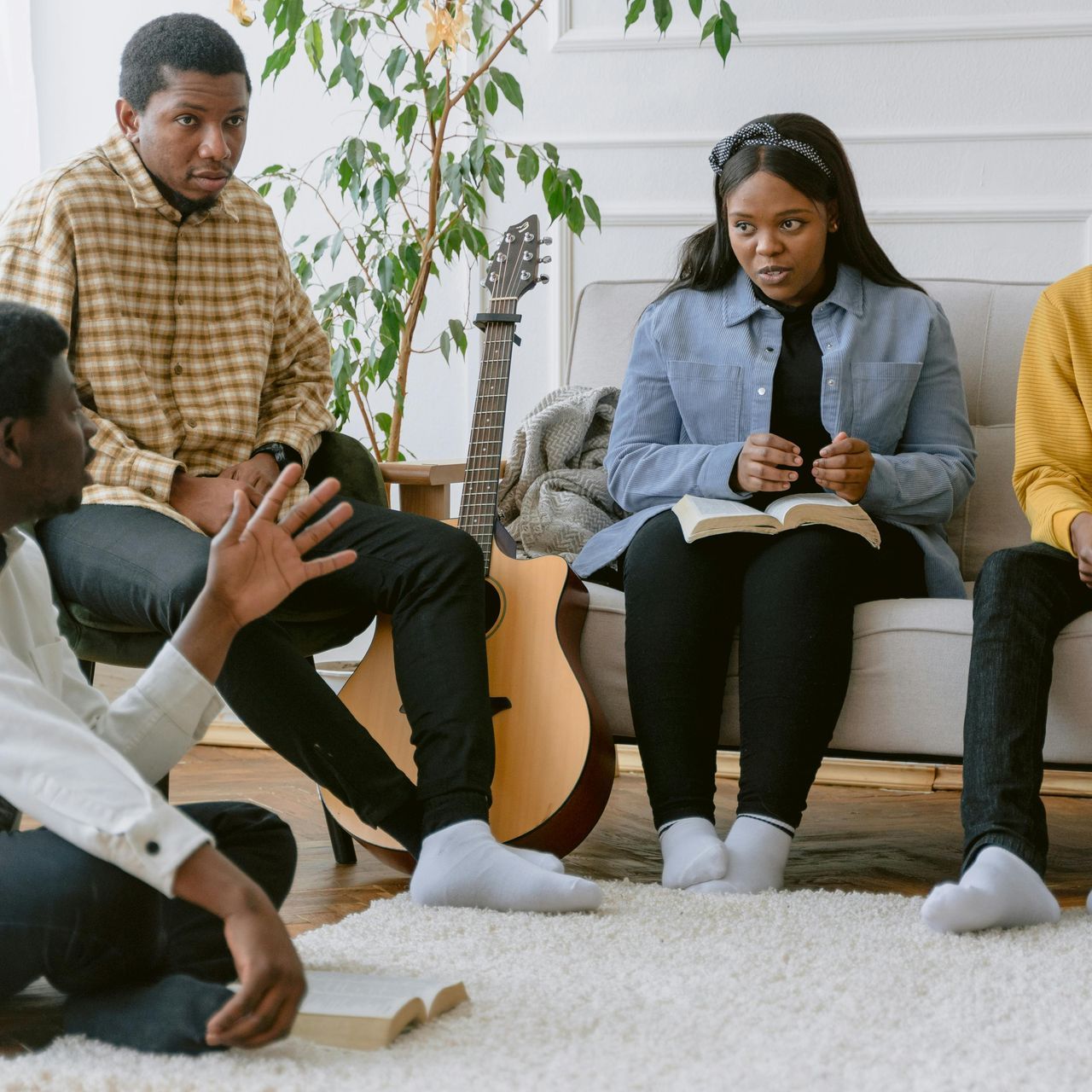 A group of people are sitting on a couch with a guitar.