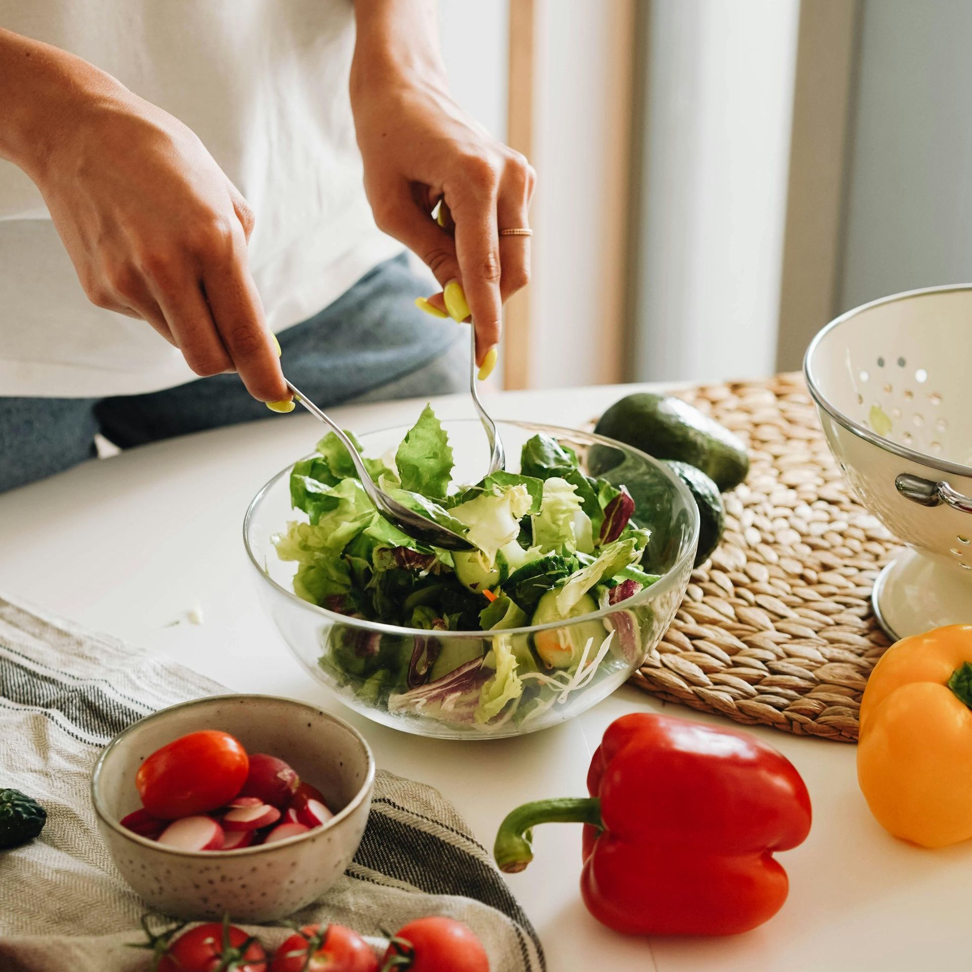 A person is mixing a salad in a bowl with a fork.