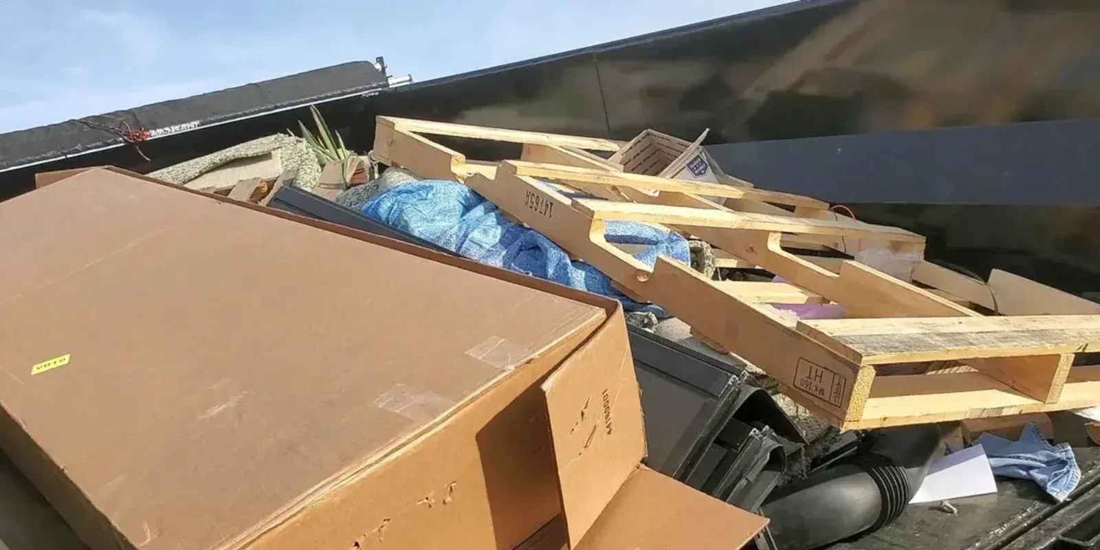 A large cardboard box and a wooden pallet resting in the back of a truck bed.