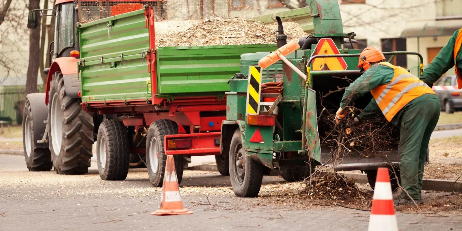 A close-up view of a black metal trailer bed filled with small, dark gray gravel, featuring a mechanical metal crank handle.
