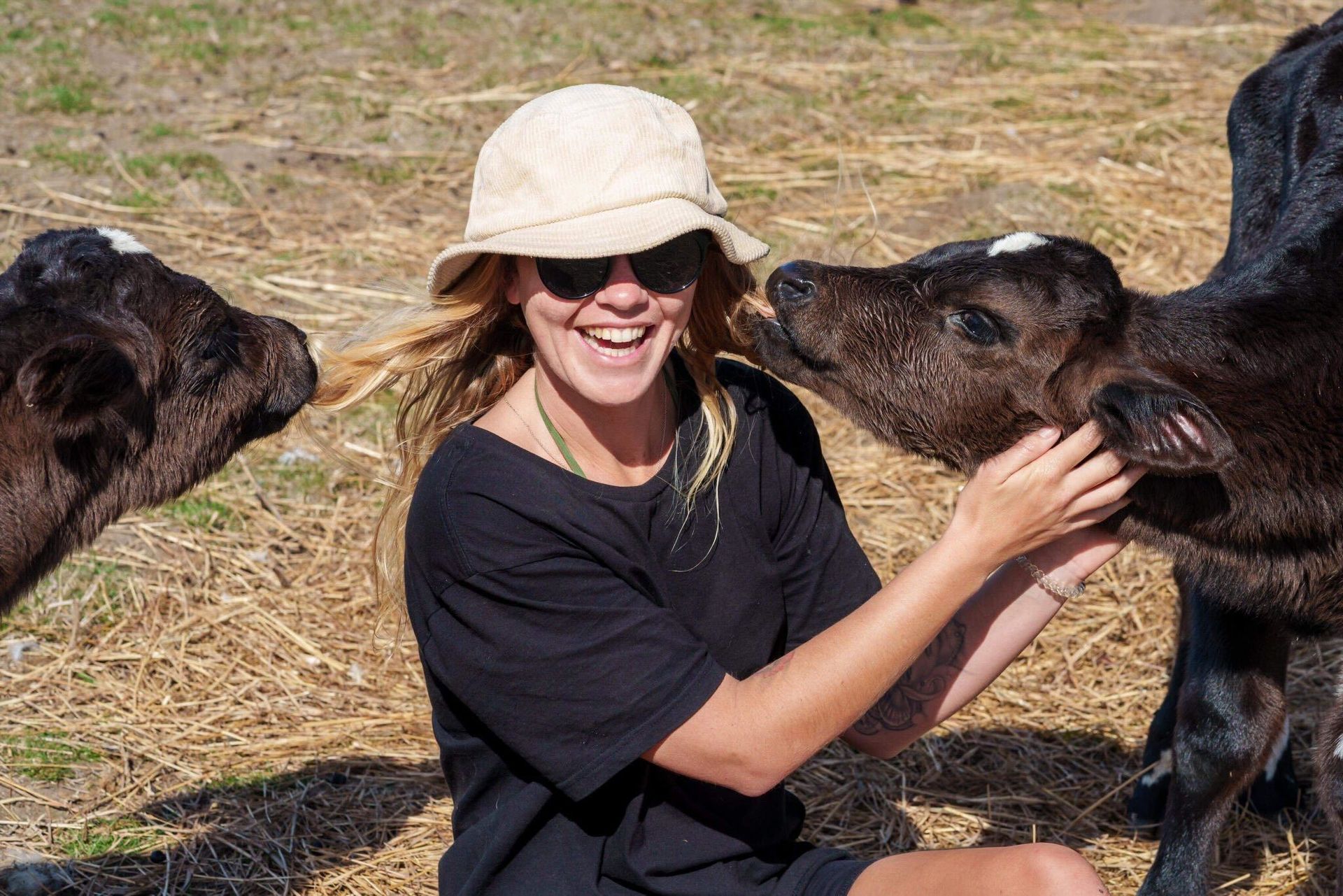 A woman is petting a baby cow in a field.