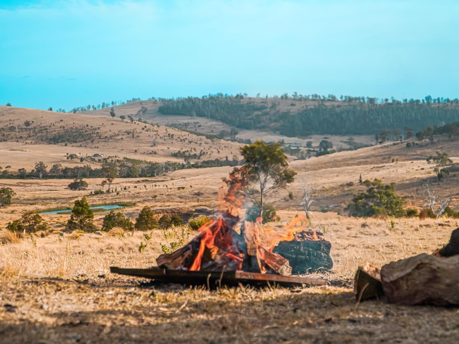 A campfire is sitting in the middle of a dry grassy field.