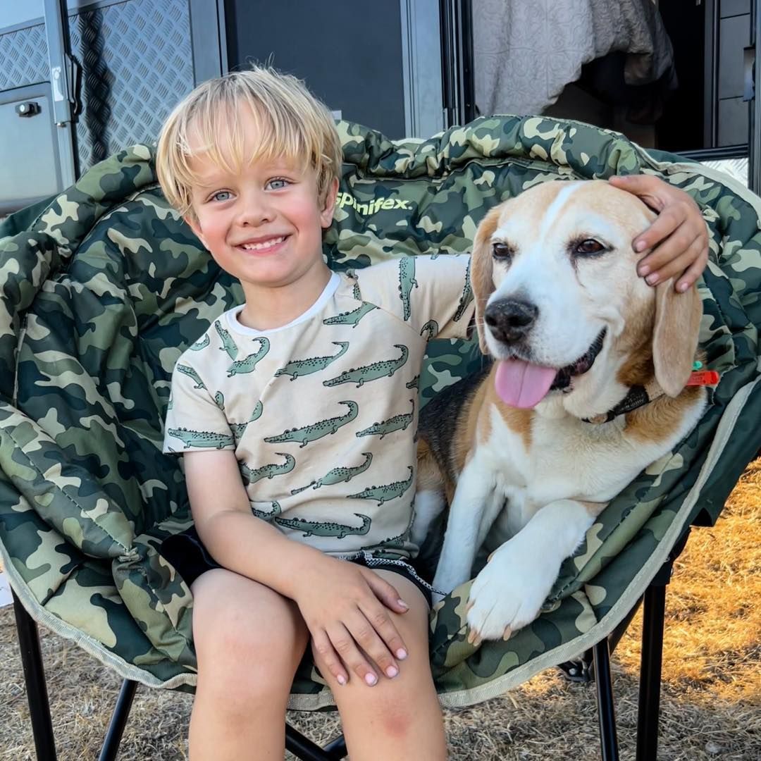 A young boy is sitting in a chair with a dog