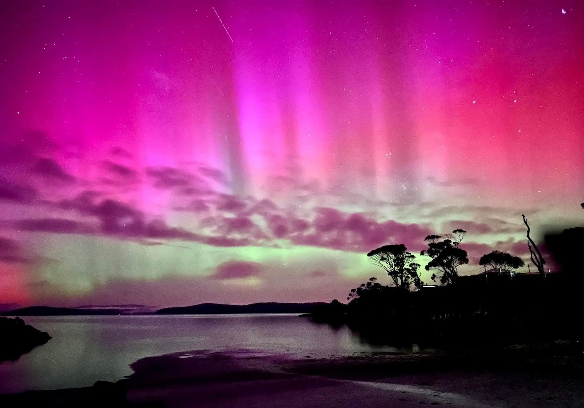 A purple and green aurora borealis over a body of water