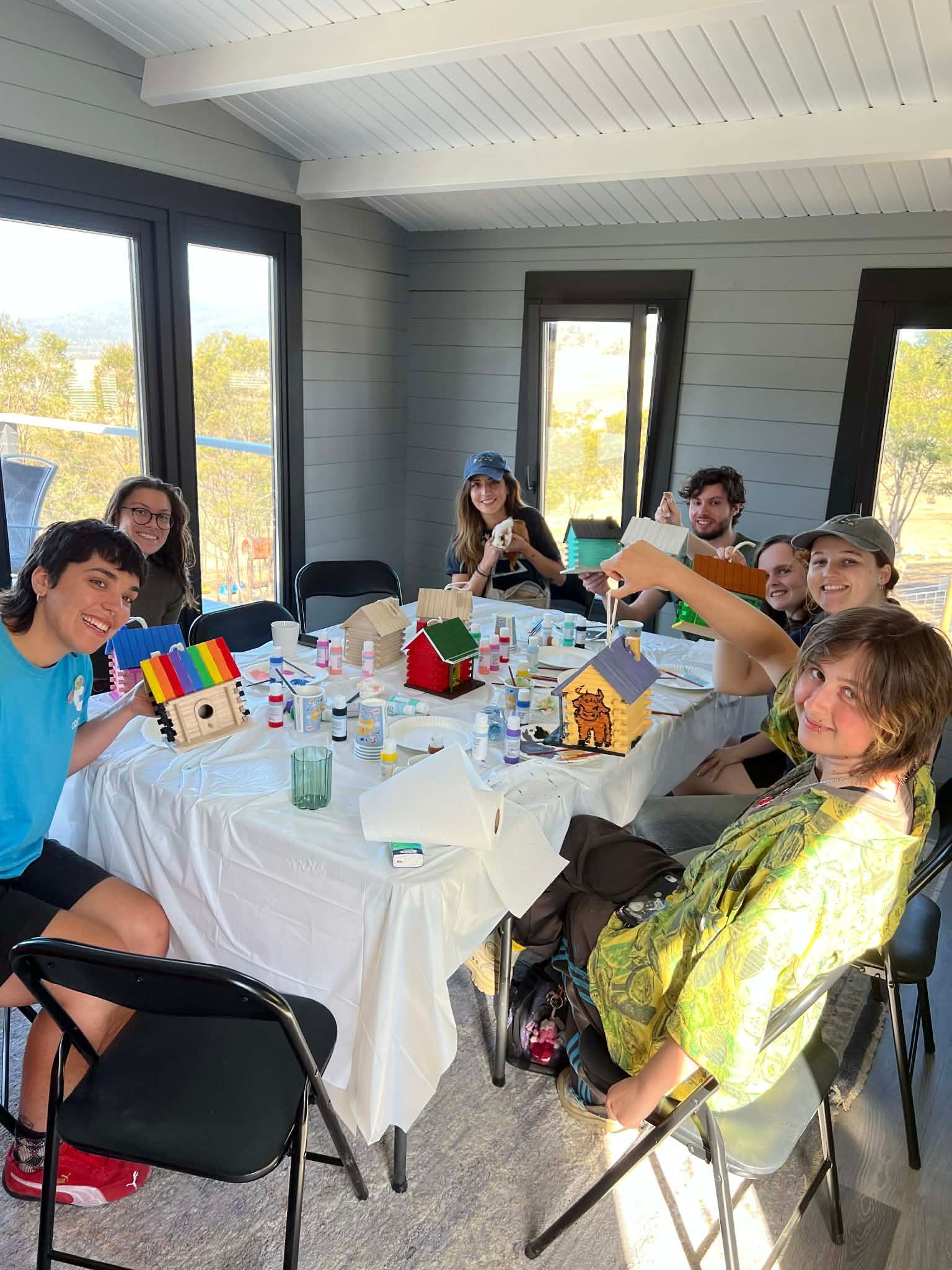 A highland cow with long horns is standing in a field next to a white goose.