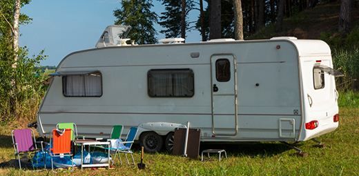 A white rv is parked in a grassy field.