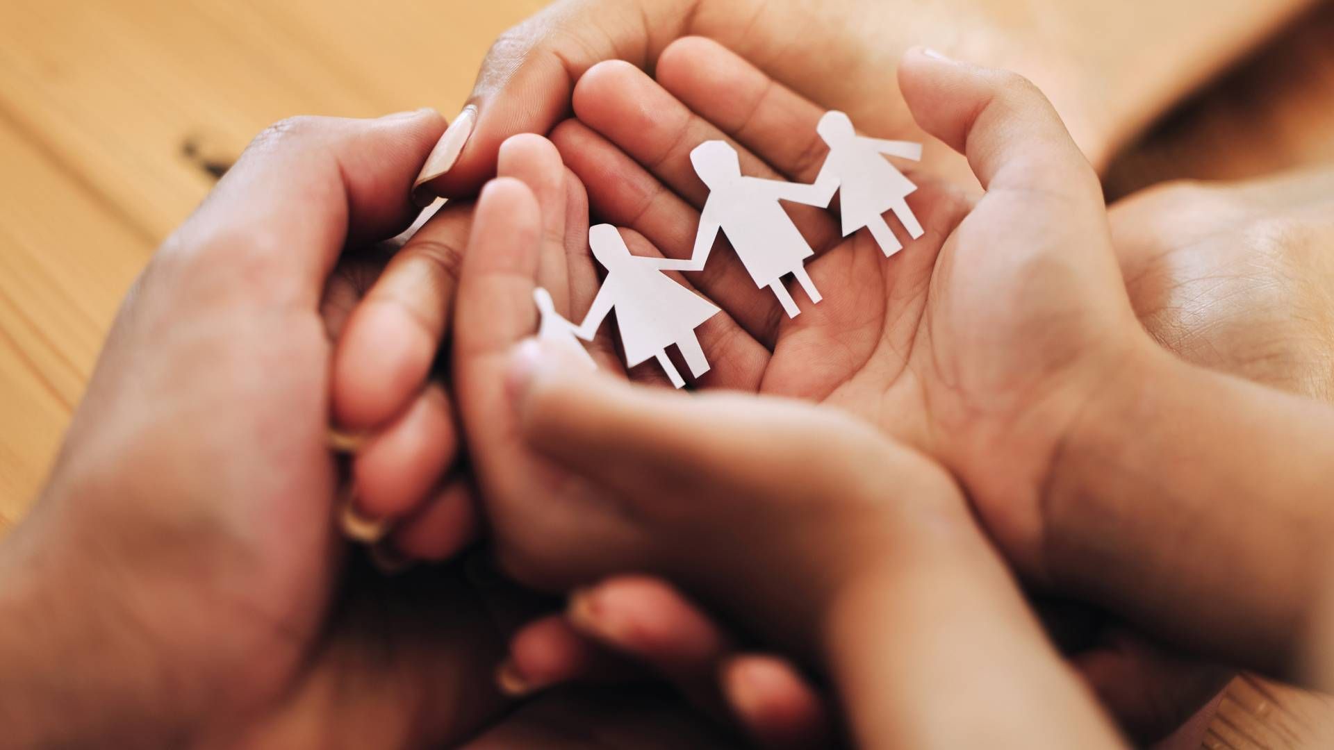 A group of people are holding paper people in their hands.
