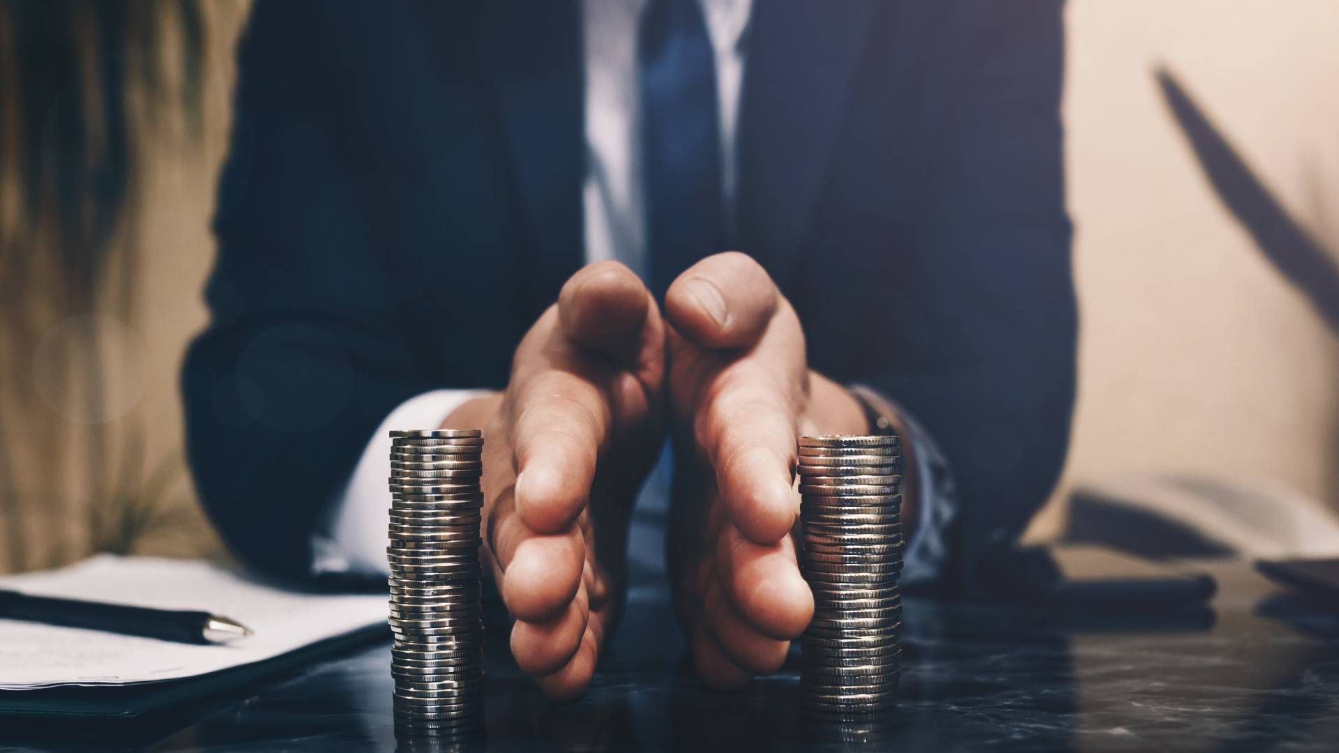 A man in a suit and tie is holding a stack of coins in his hands.