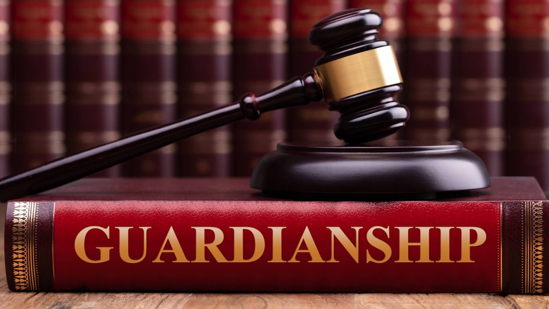 A judge 's gavel is sitting on top of a red book titled guardianship.
