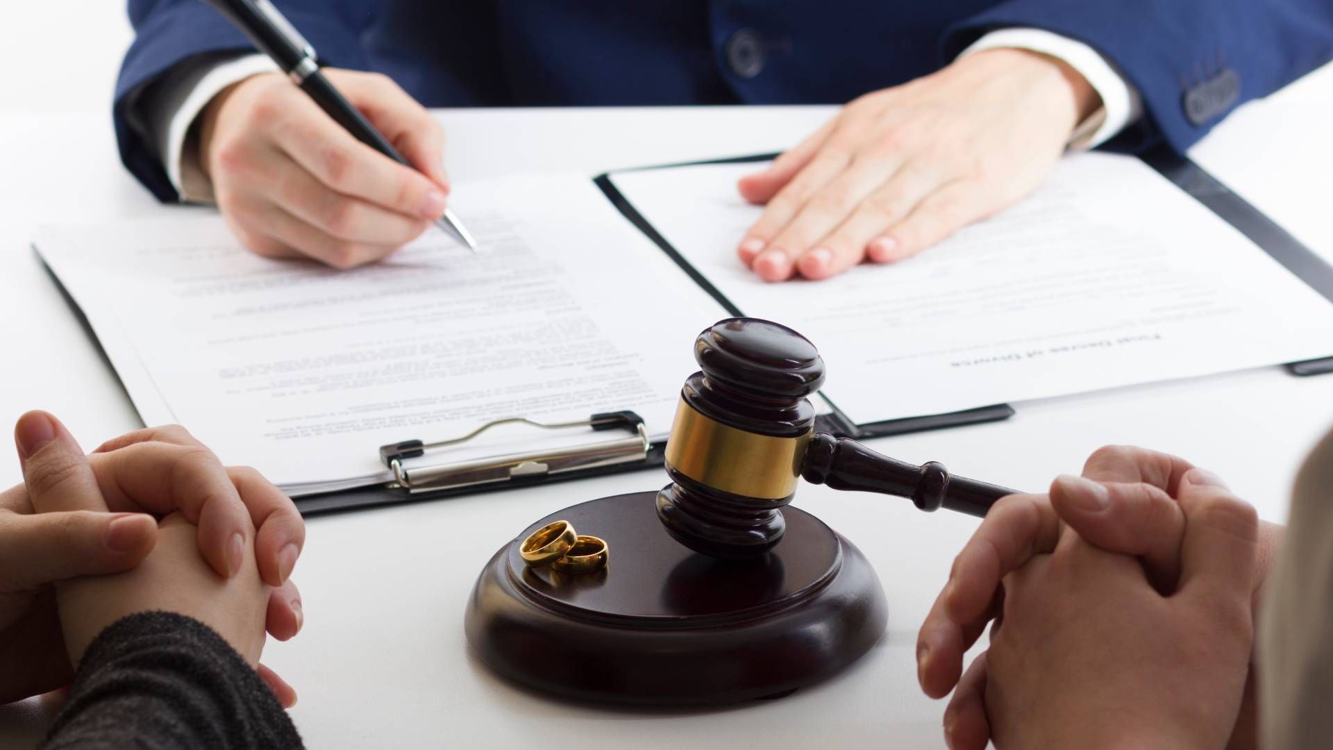 A man is writing on a clipboard next to a judge 's gavel.