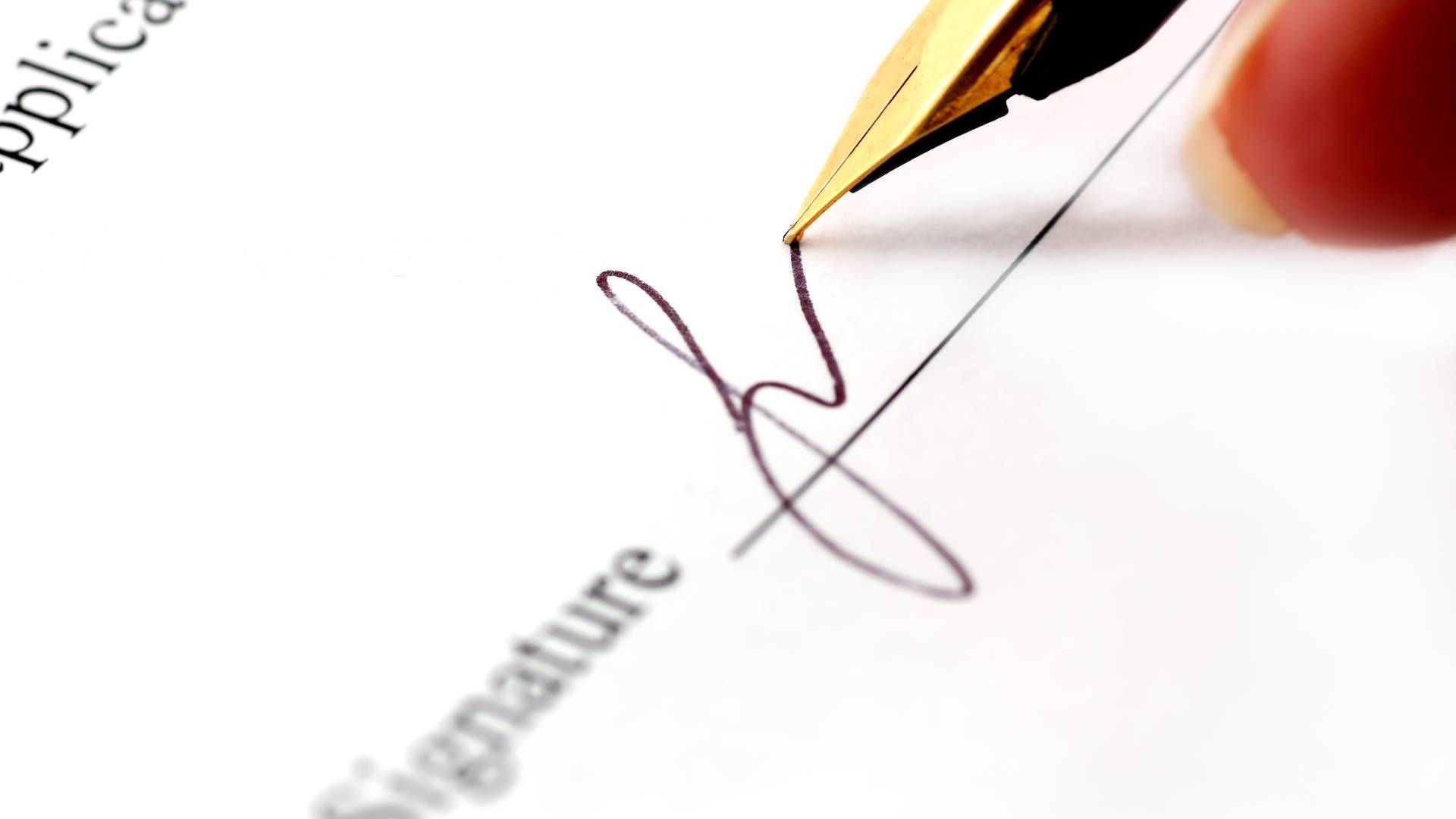 A person is signing a document with a fountain pen