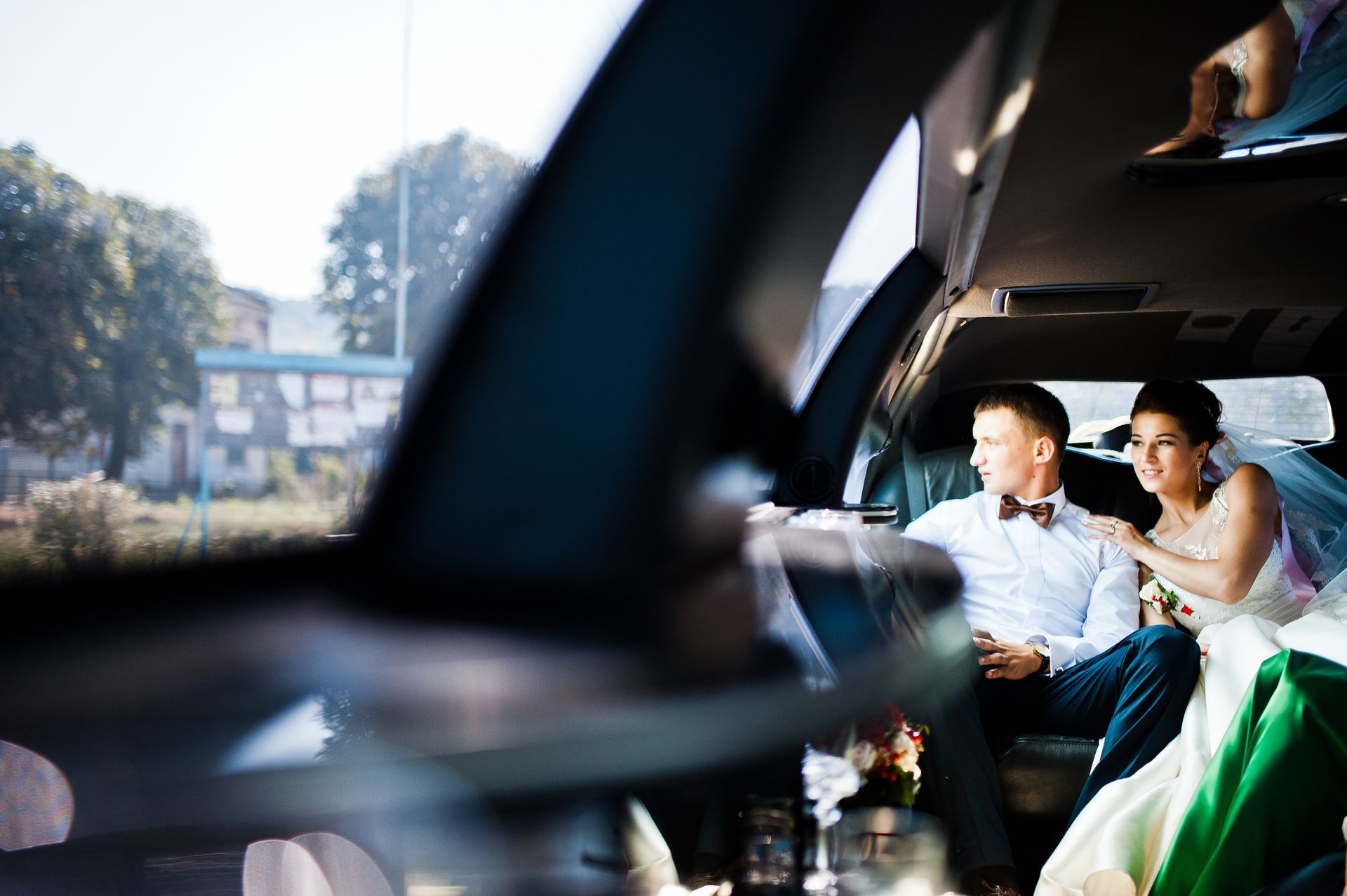 Two people seated in a car, looking out the window at a city street.