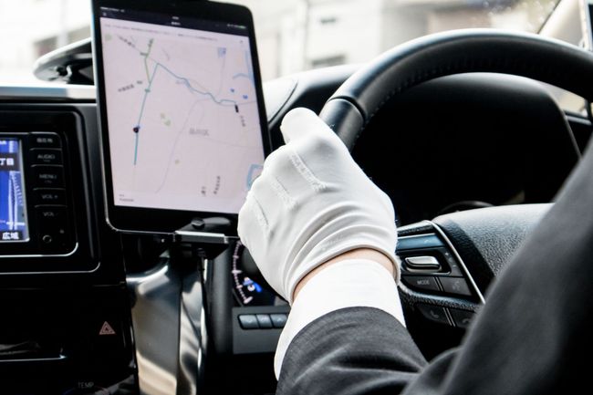 Gloved driver using a tablet GPS while steering a car on the road