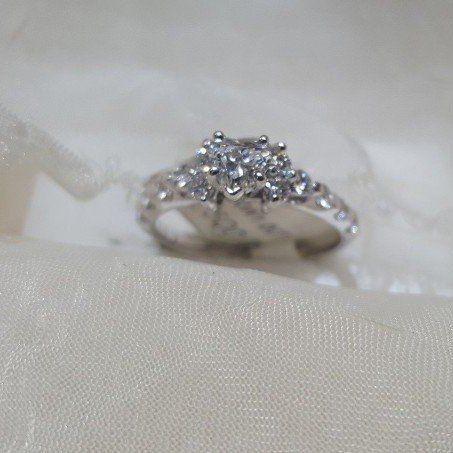 A close up of a diamond ring on a white cloth