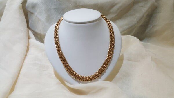 A gold necklace is on a white mannequin