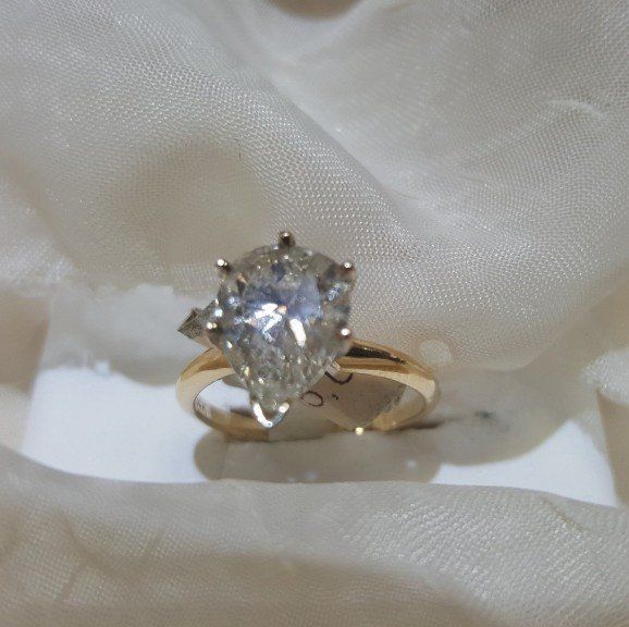 A gold ring with a pear shaped diamond in the center