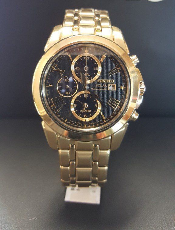 A gold seiko watch with a black face