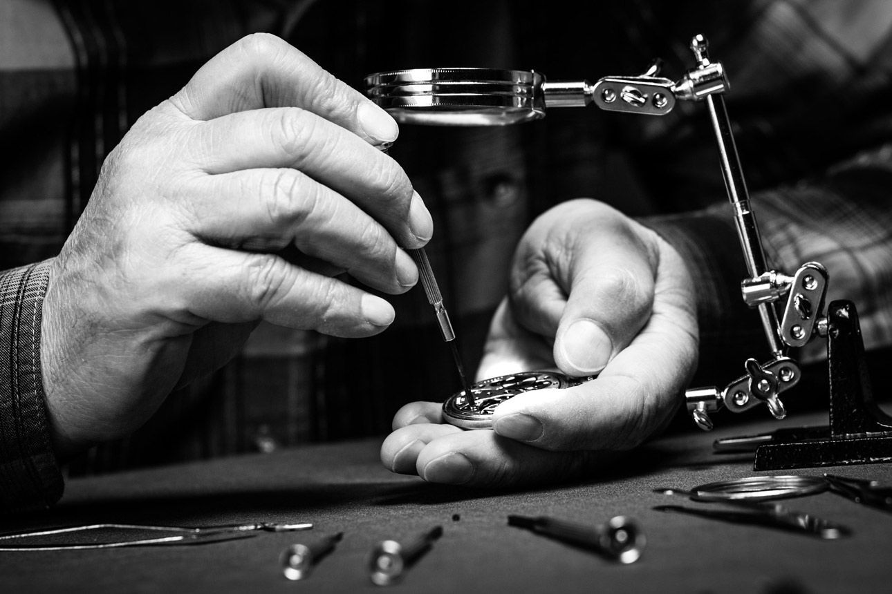 A man is working on a watch with a magnifying glass