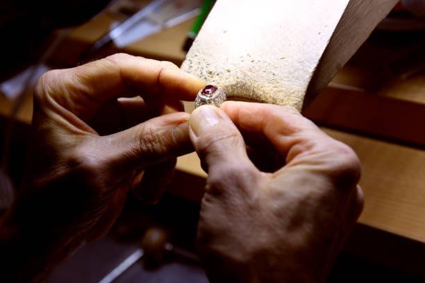 A person is working on a ring with a red stone