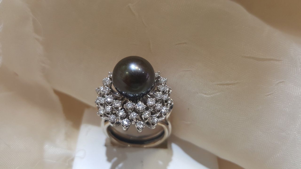 A ring with a black pearl and diamonds on it