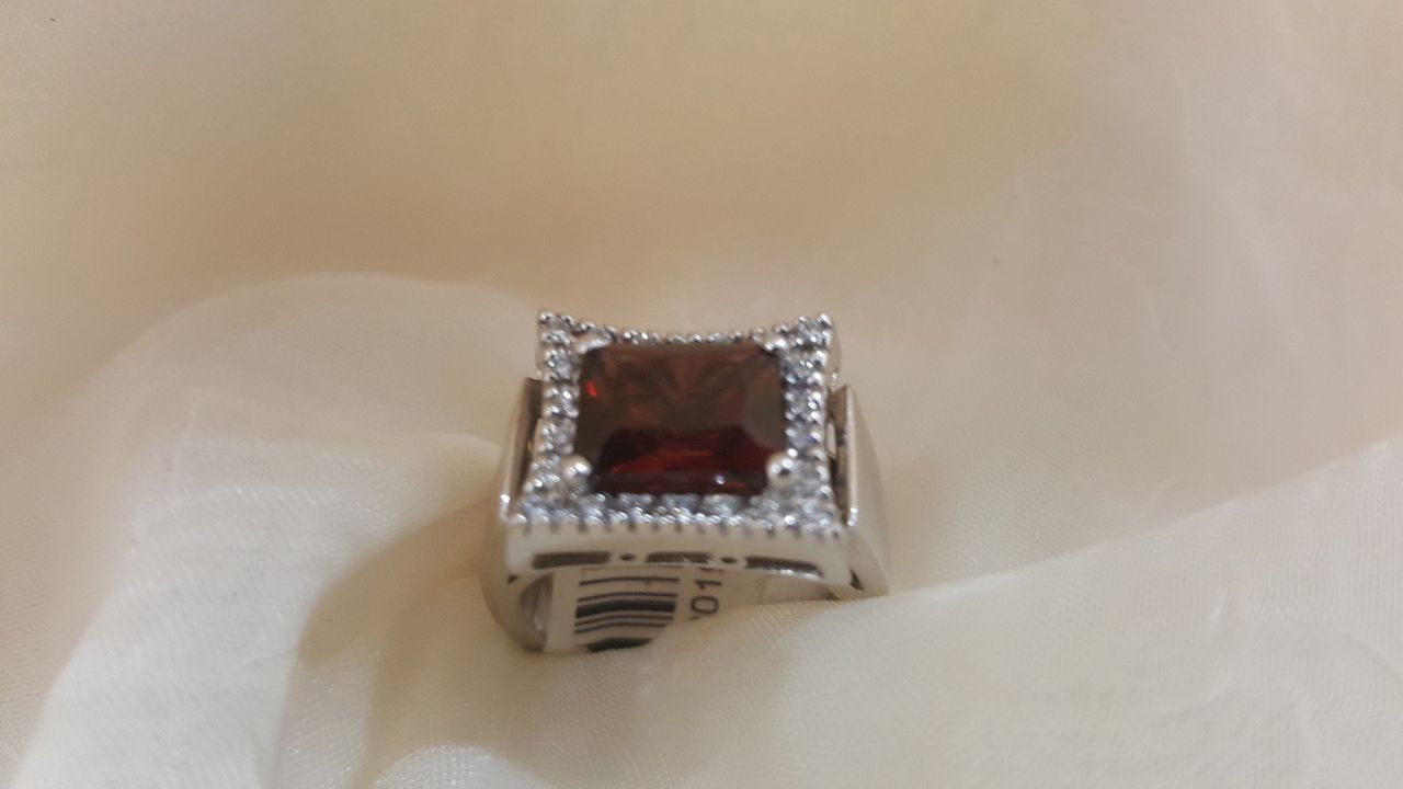 A silver ring with a red stone and diamonds