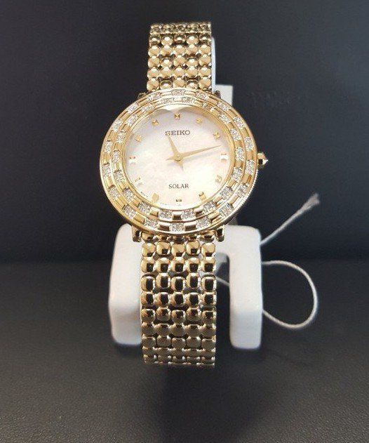 A gold watch with diamonds around the face is on display