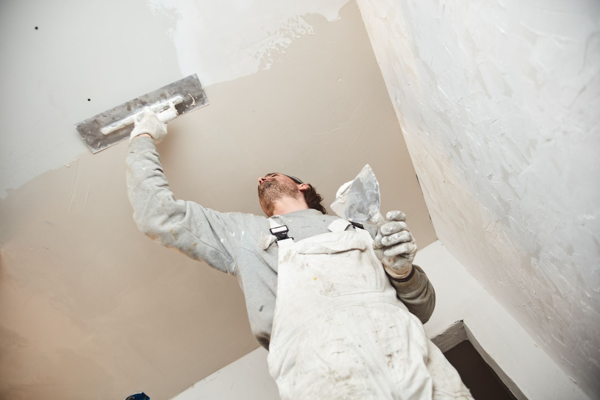 A man is plastering a wall with a trowel.