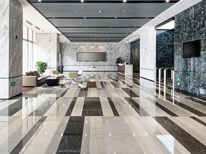 A large lobby with a marble floor and a television on the wall.