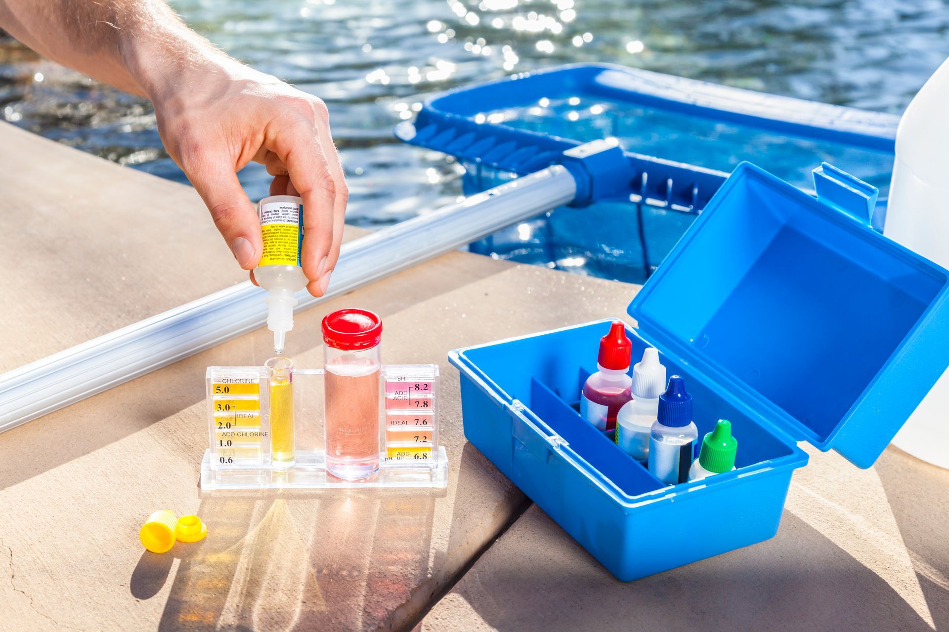 Close-up of a worker performing swimming pool water treatment, testing the quality of a pool water.