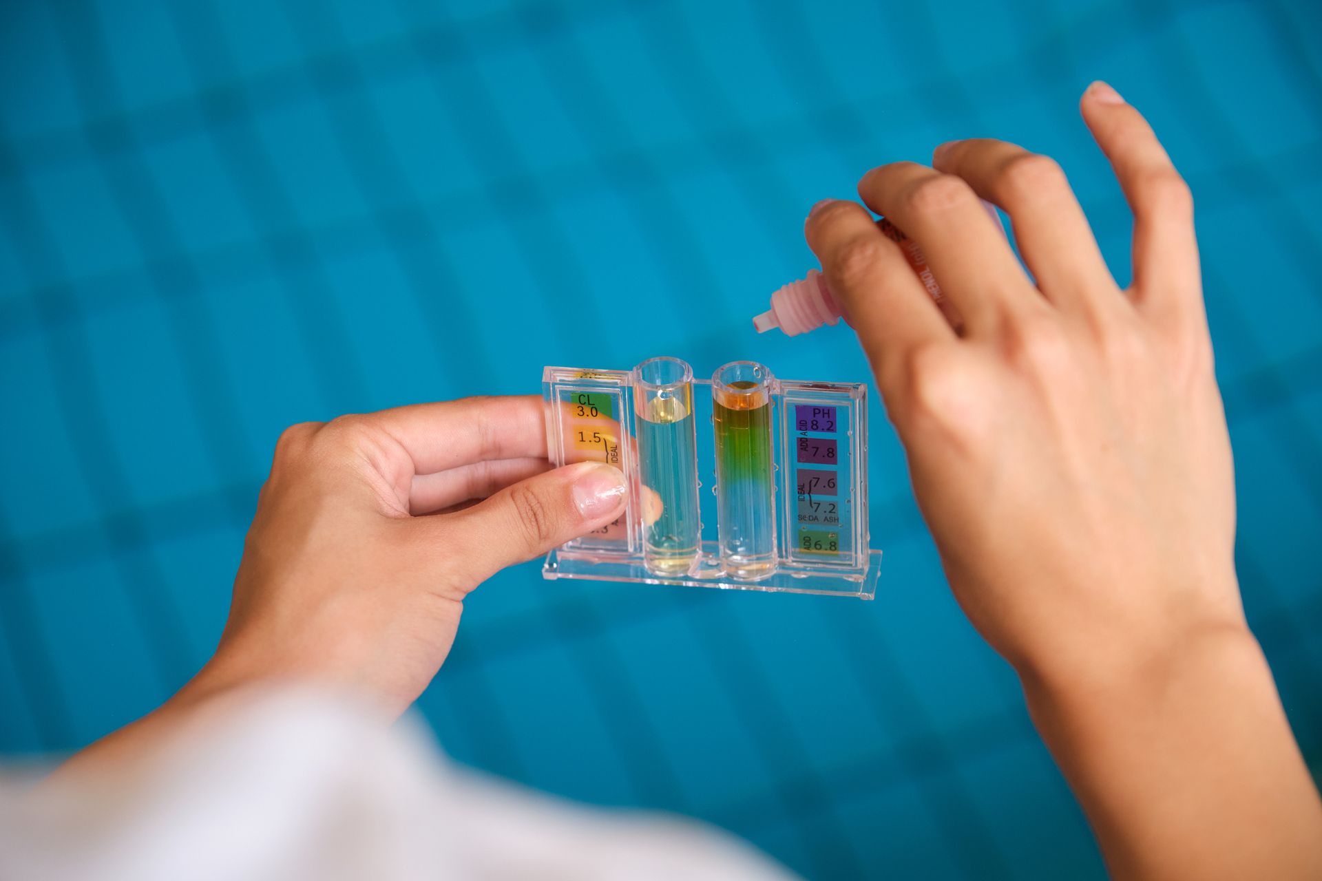 A technician adding reagent to test tubes for chlorine and ph control in a swimming pool. A technician adding reagent to test tubes for chlorine and ph control in a swimming pool.