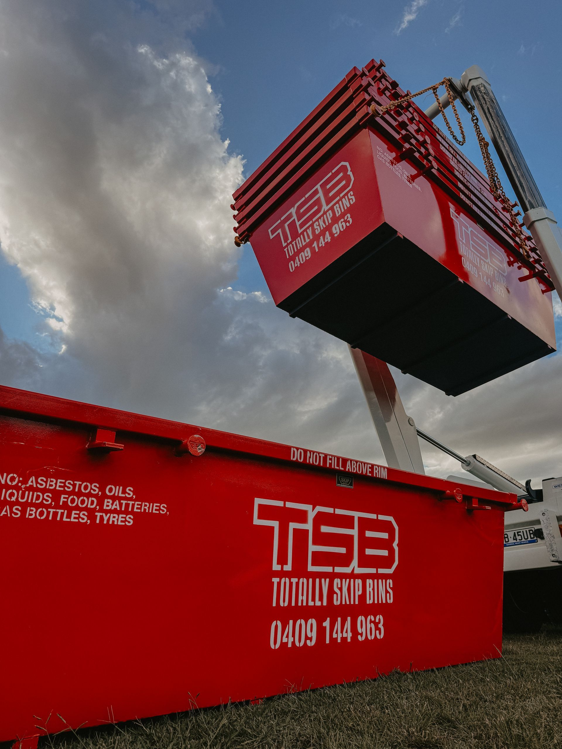 A Red Dumpster is Being Lifted by a Crane — Totally Skip Bins in Palen Creek, QLD