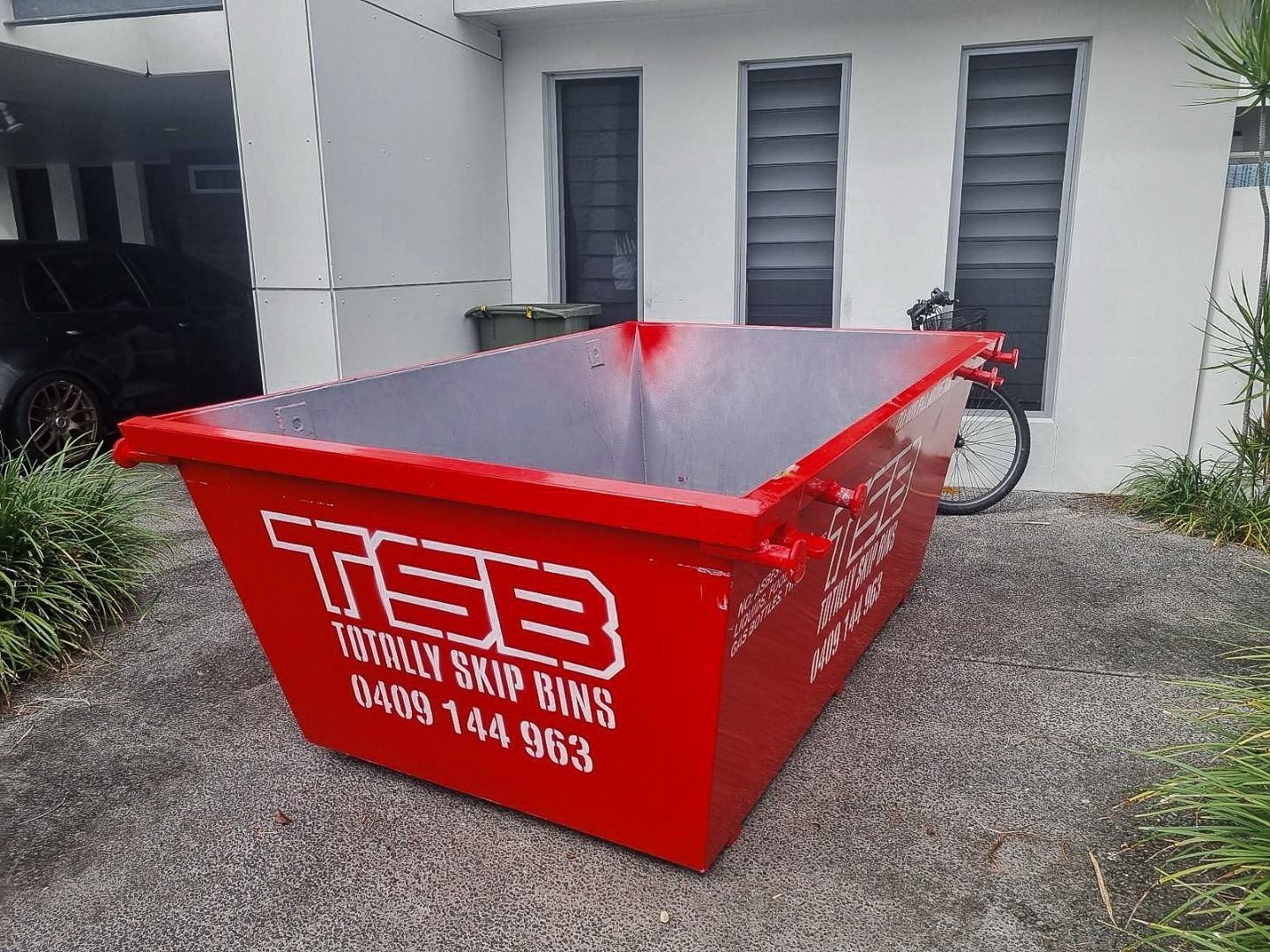 Red Skip Bin Outside a House