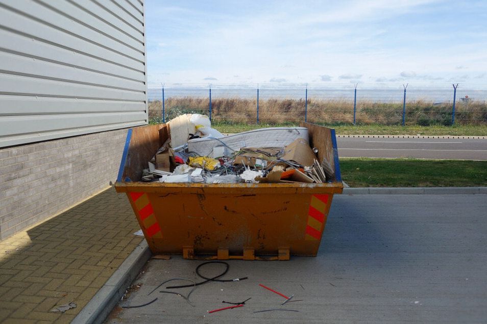 A Dumpster Filled With Trash is Parked in Front of a Building — Totally Skip Bins in Beaudesert, QLD